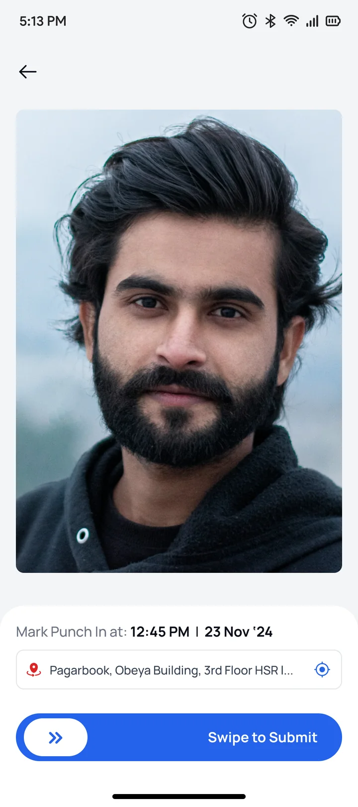 A staff member marking his own attendance in the app, his face on screen above the swipe to submit control, with the time and site stamped underneath